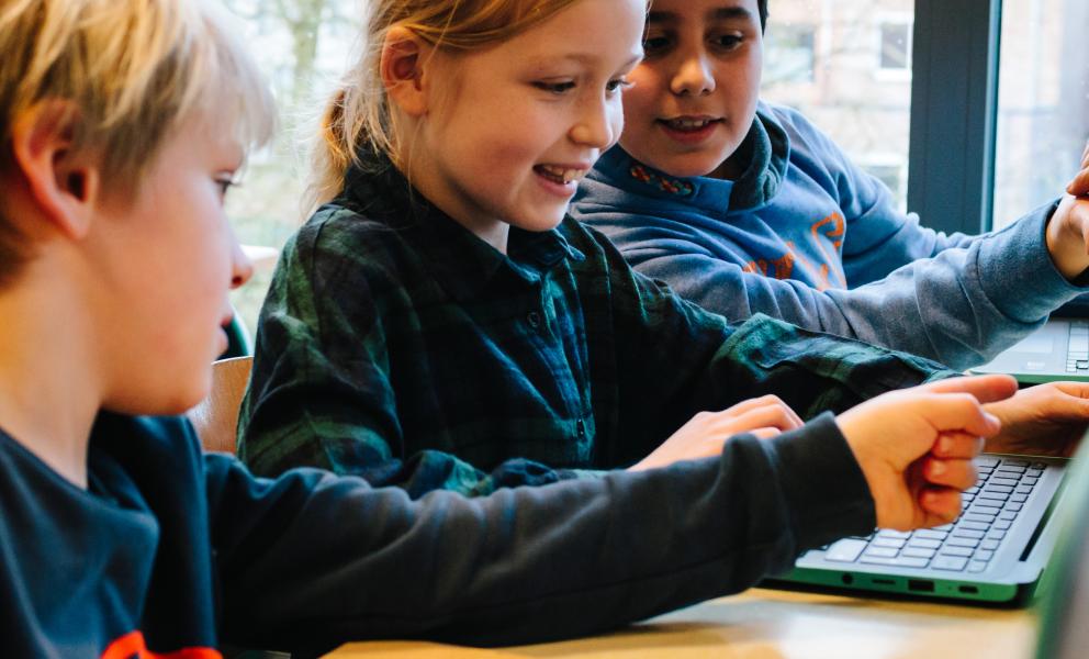 Kinderen werken samen aan laptops