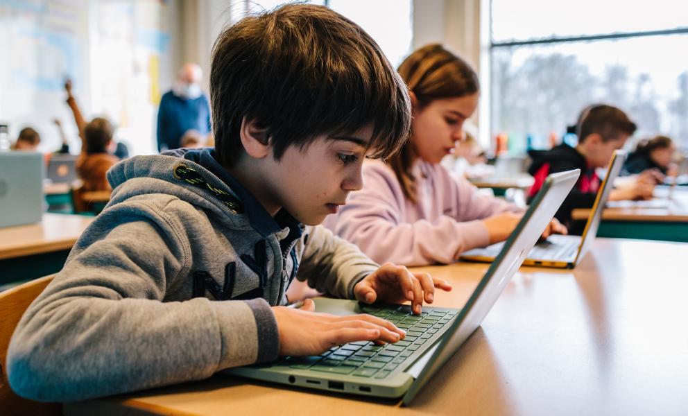 Jongen werkt op een laptop in de klas