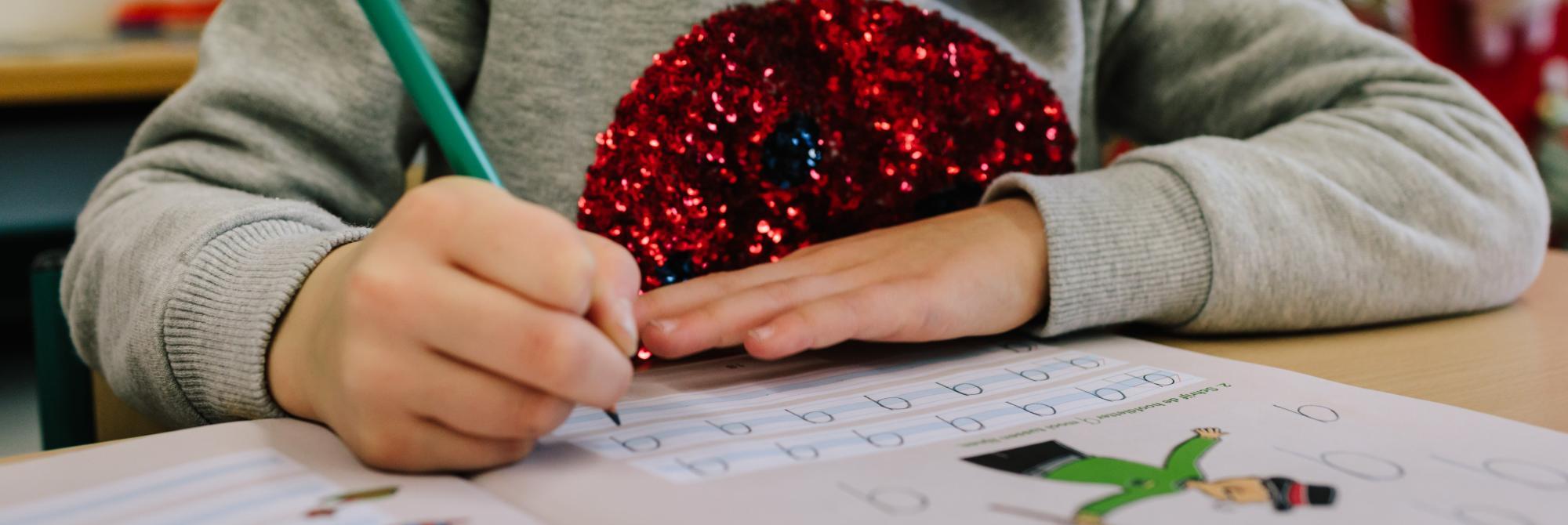 Kind oefent met schrijven van hoofdletter Q