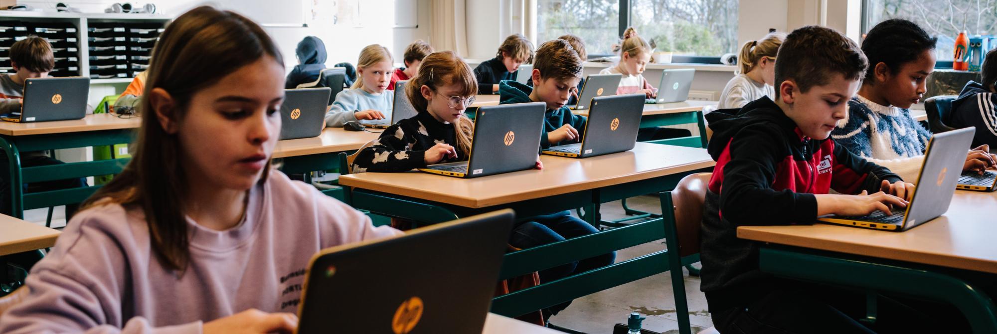 Kinderen in de klas werken op laptops